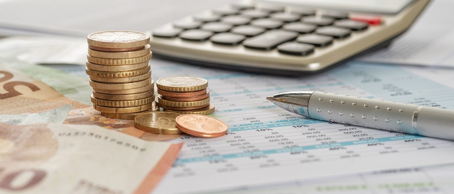 Geld mit Taschenrechner und Kugelschreiber