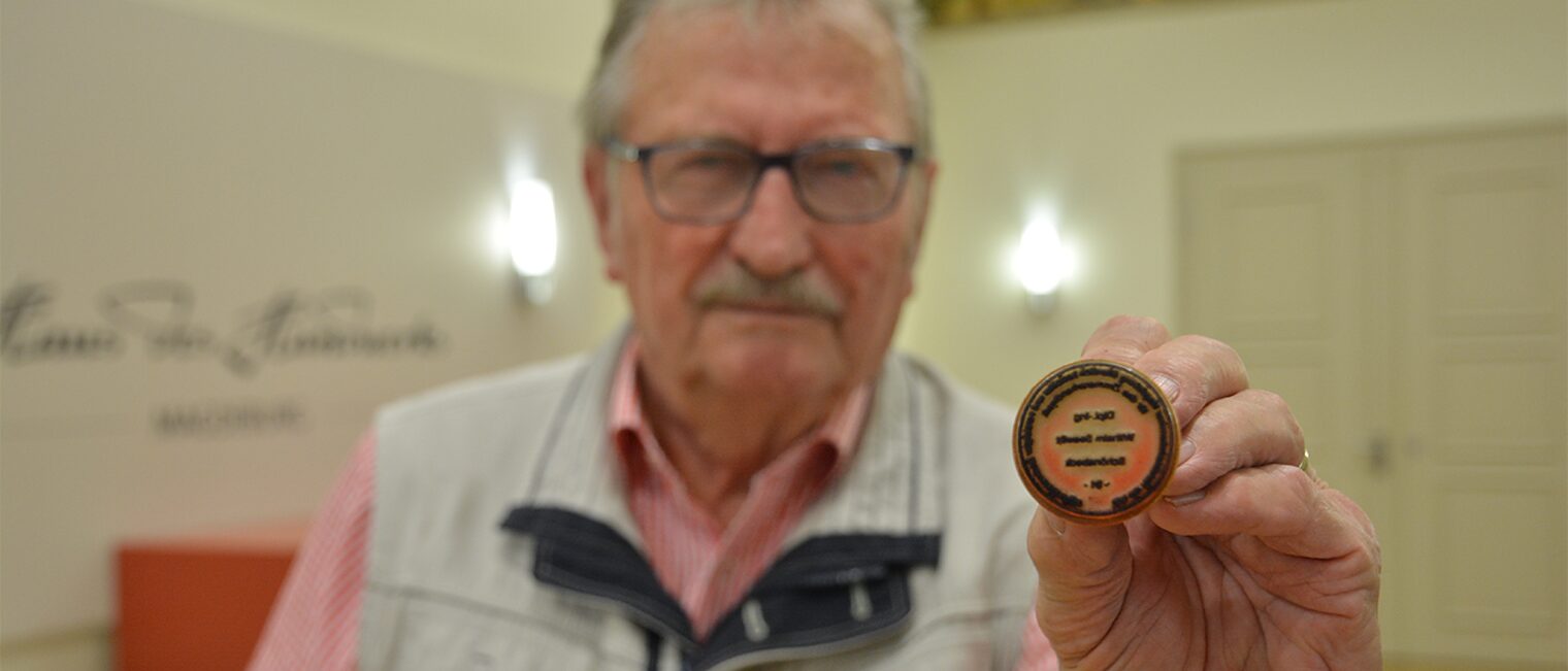 Der Mann zeigt seinen Sachverständigen-Stempel.